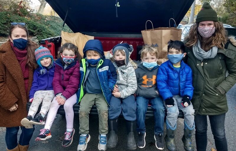 a group of children and two adults sit in the trunk of a car filled with food